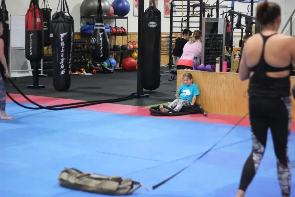 a child sitting in the background during a women only fitness class at functional fitness eltham highlighting a kid friendly environment