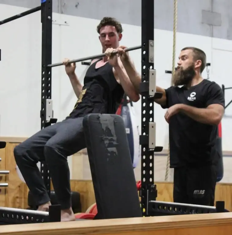 personal trainer assisting client with pull up technique at functional fitness eltham