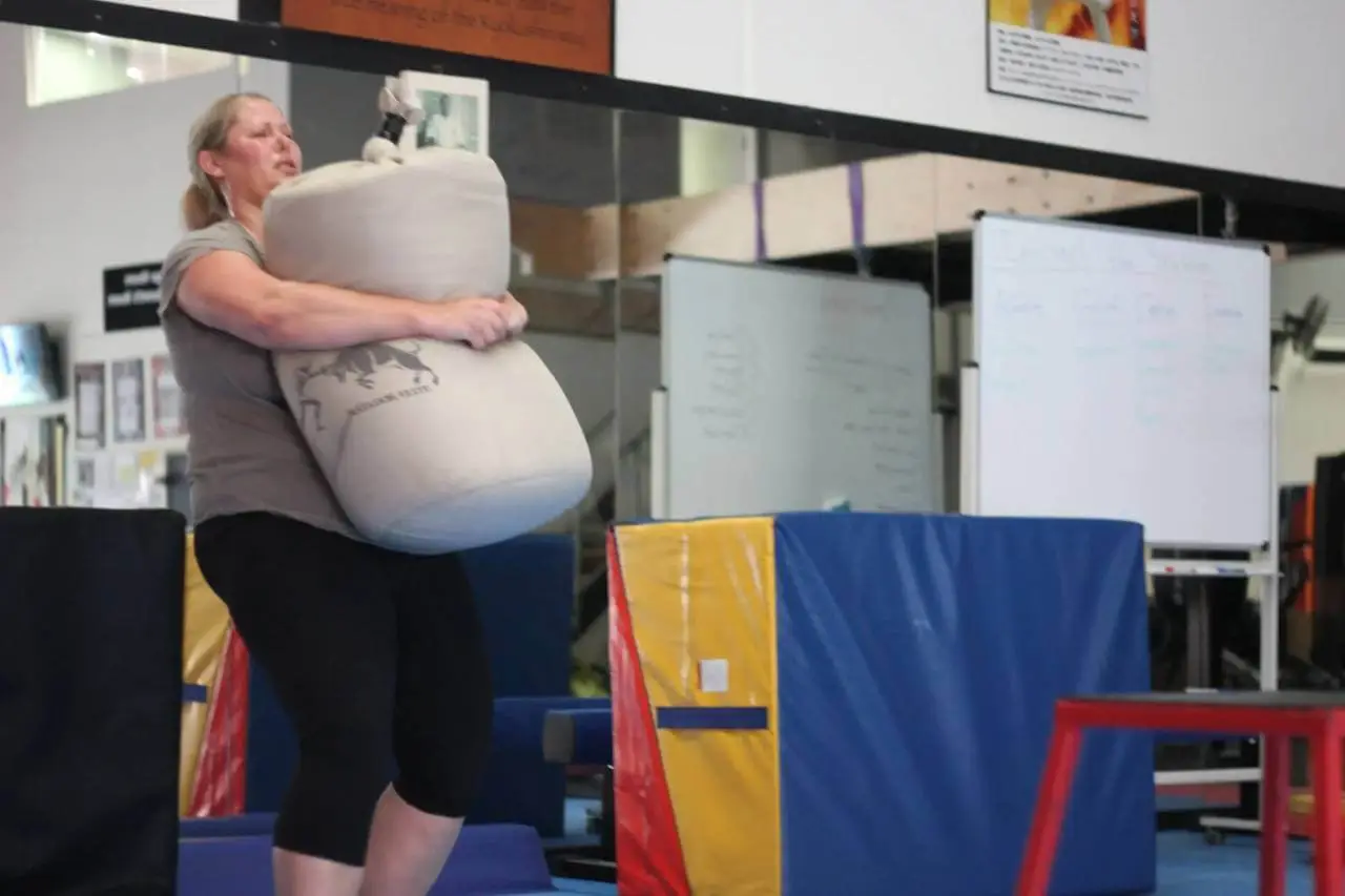 woman carrying a heavy sandbag during a women only fitness class at functional fitness eltham focusing on strength and endurance training