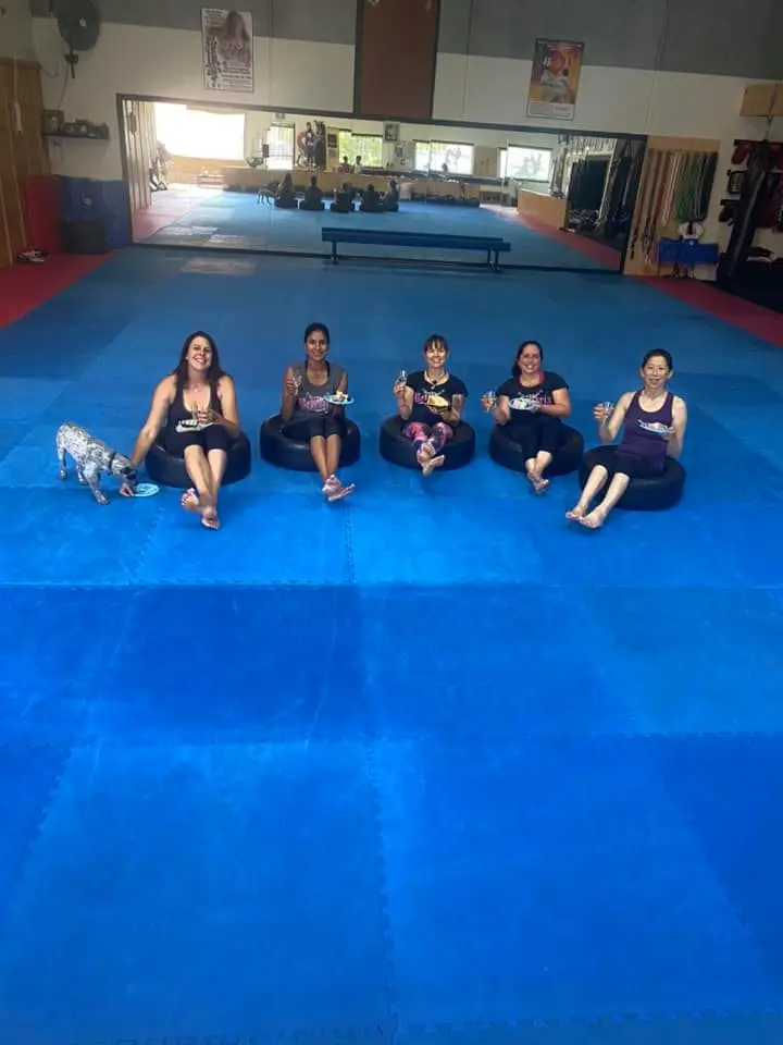 women sitting on tires enjoying cake after a workout during a women only fitness class at functional fitness eltham with a relaxed and social atmosphere