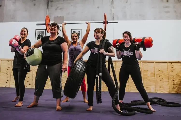 women smiling and holding fitness equipment during a women only fitness class at functional fitness eltham showing a strong and fun group dynamic